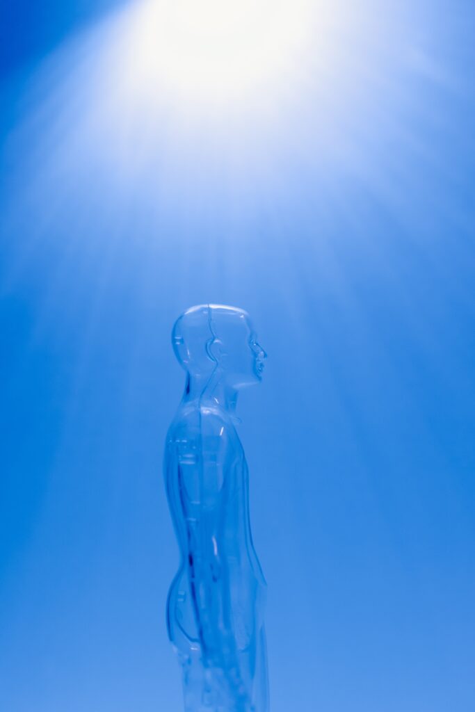 Image a clear male mannequin facing to the side against a blue background, with light shining through it