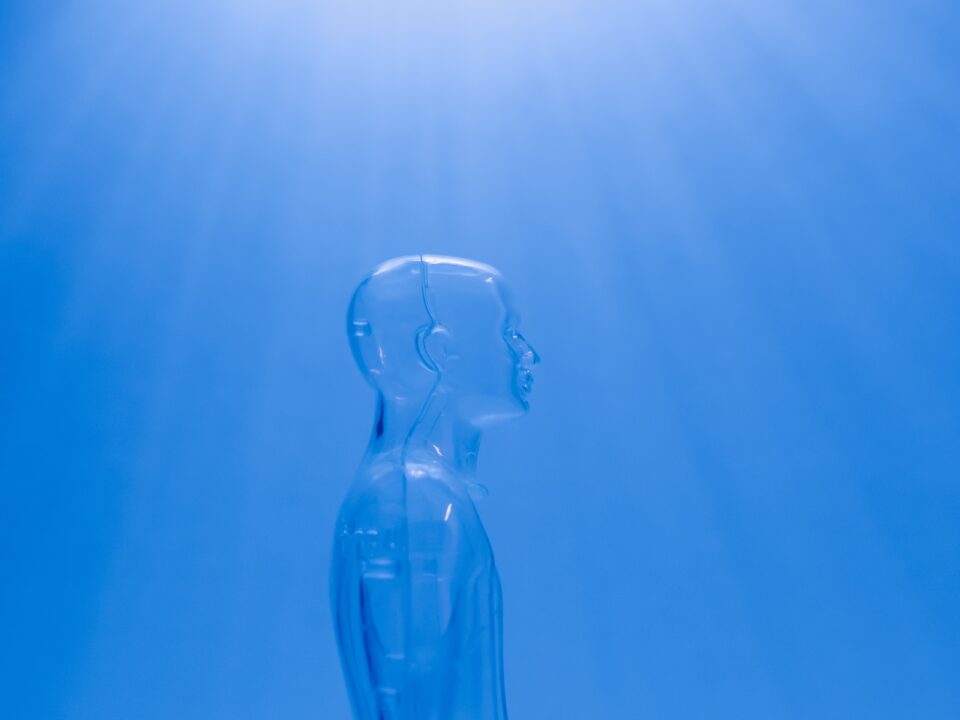 Image a clear male mannequin facing to the side against a blue background, with light shining through it